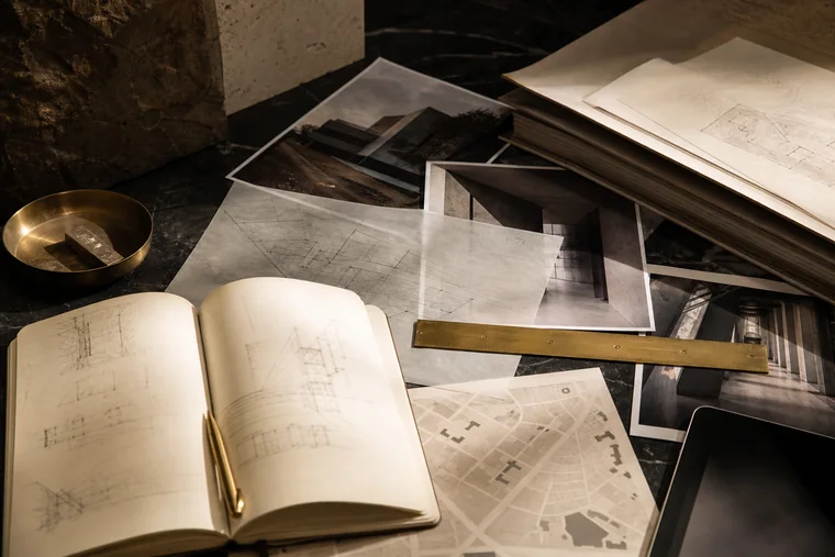 Planos, mapas y documentos superpuestos sobre una mesa de piedra oscura