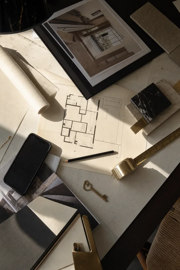 Mesa de trabajo con planos, fotografías de propiedad, muestras de material y una llave